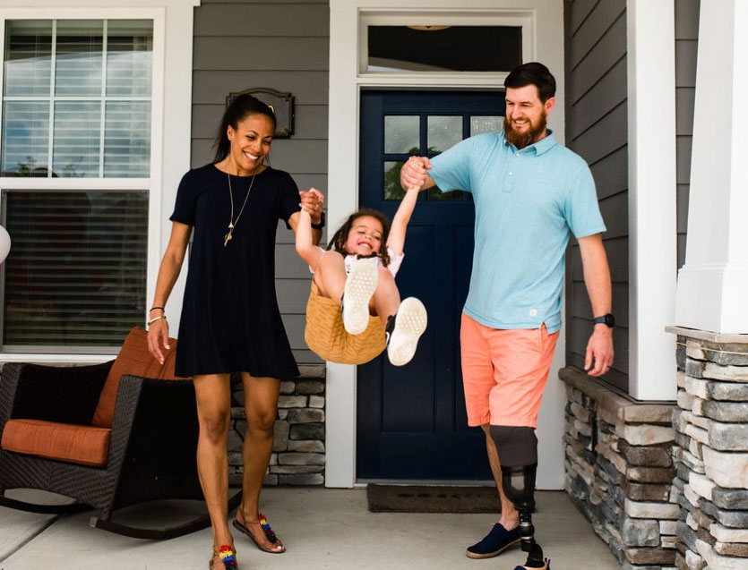 A couple in front of a house with a child